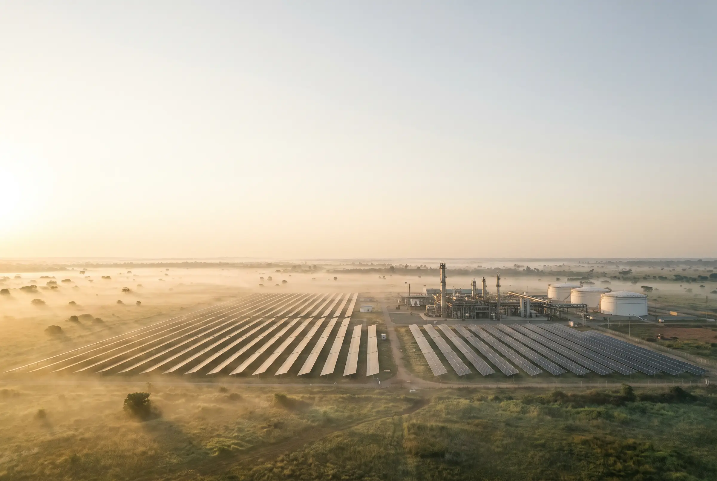 A solar farm beside a gas processing plant at sunrise